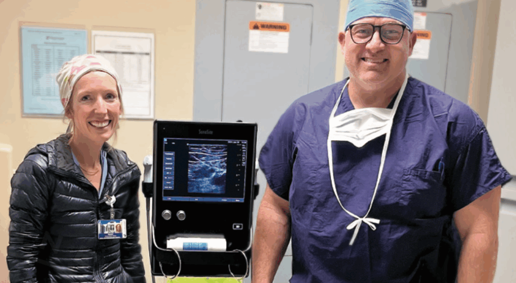 Two CRNA's smiling next to an ultrasound machine