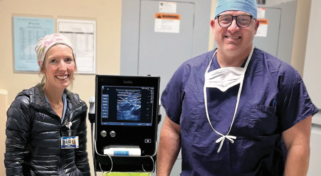 Two CRNA's smiling next to an ultrasound machine